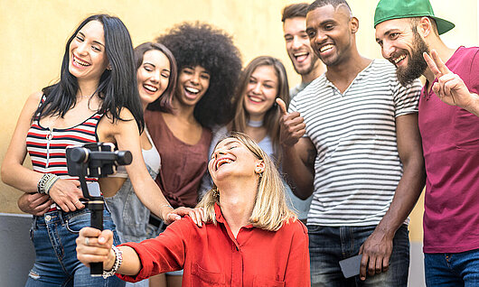 Multiracial young friends taking pictures to share on social media